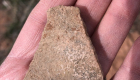 Photo of a pottery fragment held in the palm of a person's hand.