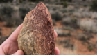 Photo of a stone cobble tool held in a person's hand.