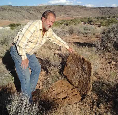 Gaylord Robb holds up a large sandstone slab that could have served as a door for a storage pit or a pit house. Credit: Chaz Evans/ The Archaeological Conservancy.