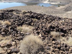 View of rocks/boulders arranged into conical formations. Lake in the background.