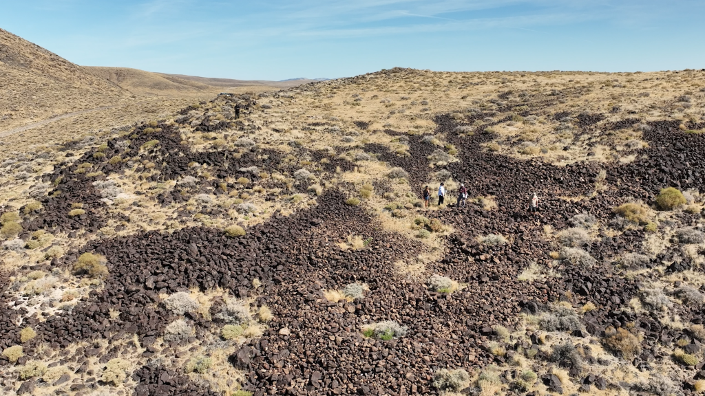 Photo of landscaep looking down to a hillside covered with dry vegetation and rocks. Obvious circular formation are seen within the rocks/boulders.