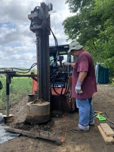 Photo of a man standing next to a large digging machine.