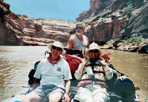 Photo of three people riding in a raft down a calm river.